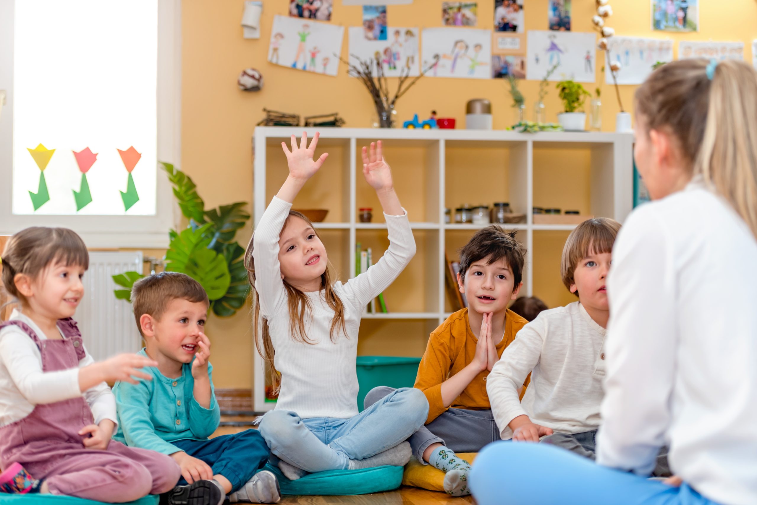 Preschool children actively engaging with their teacher in an early learning environment.