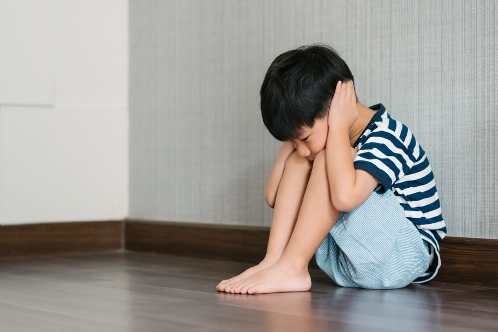 Boy covers ears in an empty room