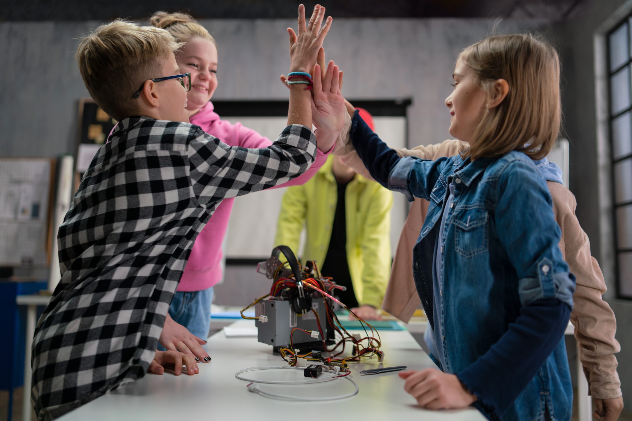 Teacher assisting children with electric toy robots in a robotics classroom.