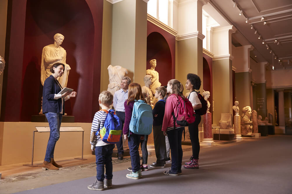 A class of students admire a statue in a museum